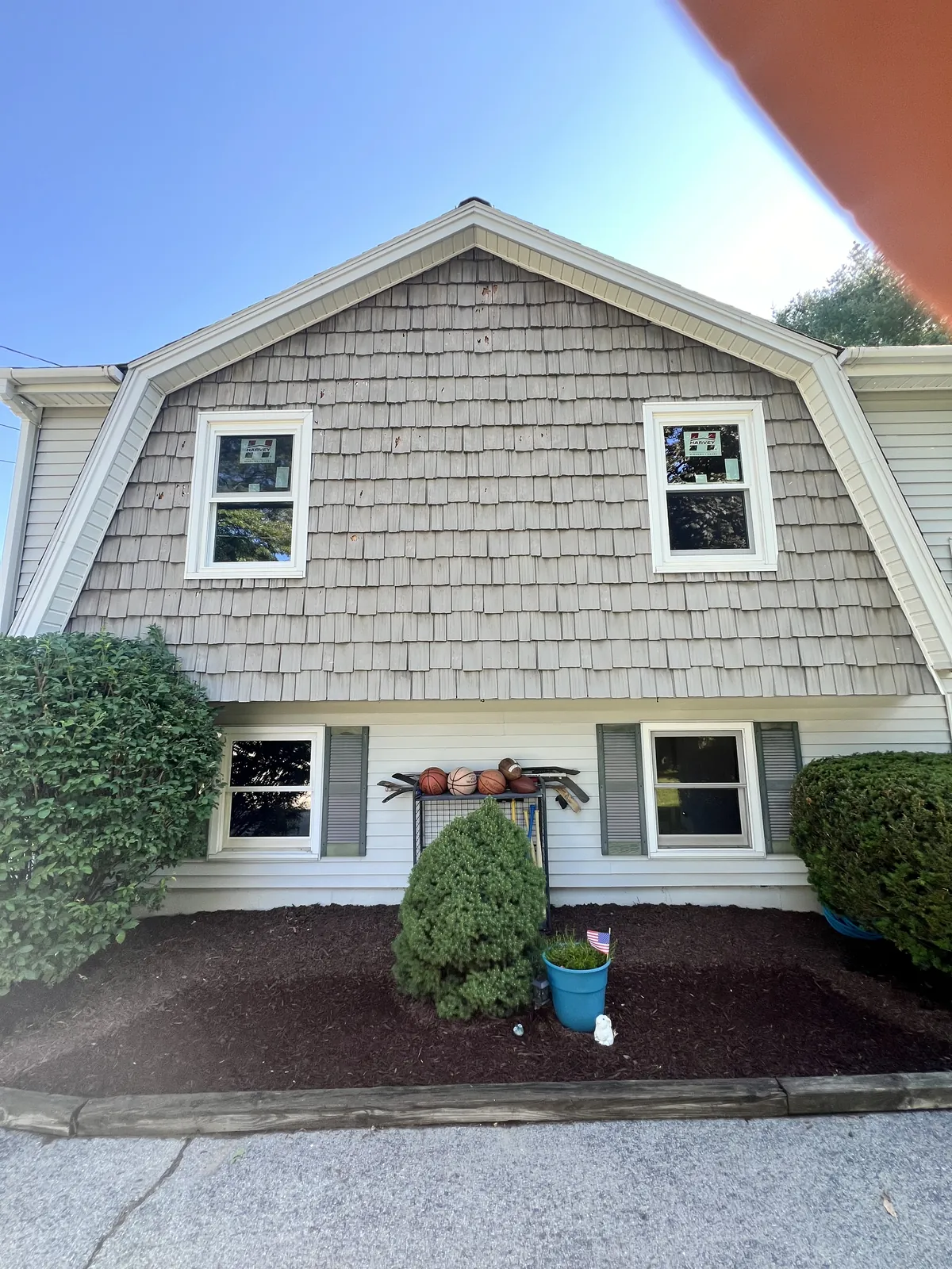 Gambrel roof home finished in cedar-tone shingle siding